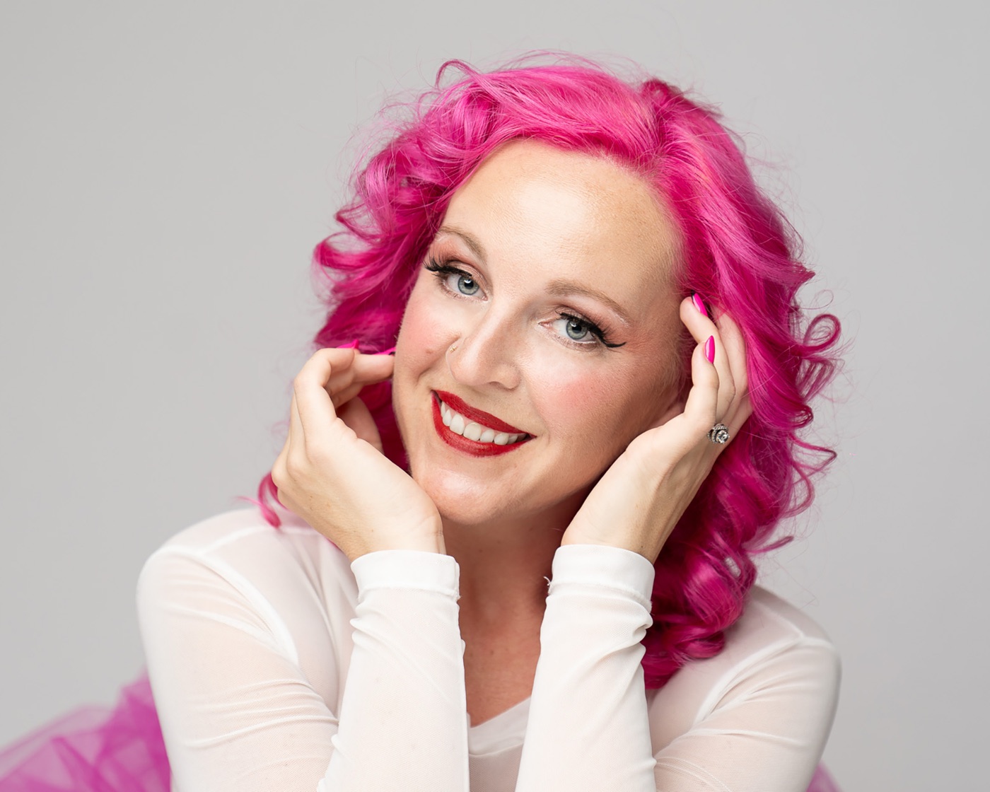 Commercial actor headshot with bright pink hair and a big smile on a grey backdrop — Look Gross Studio, Long Beach