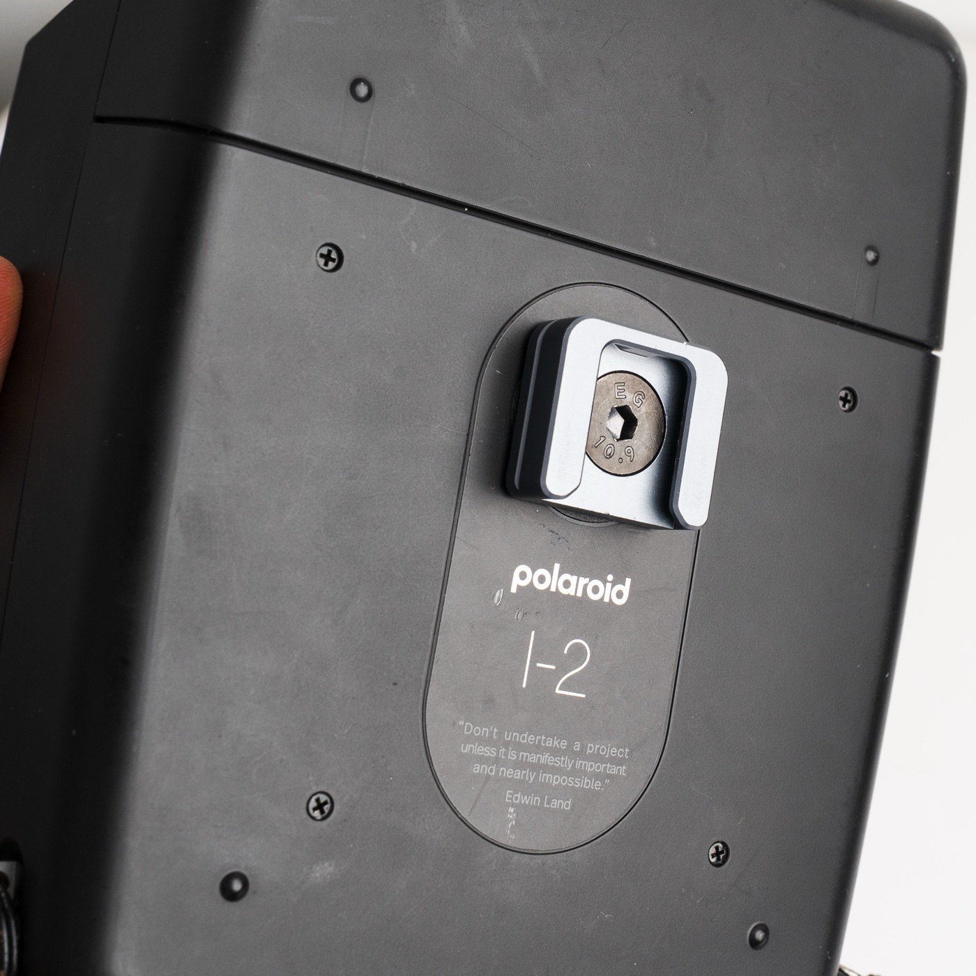 A cold-shoe mount bracket threaded into the tripod socket on the base of the Polaroid I-2