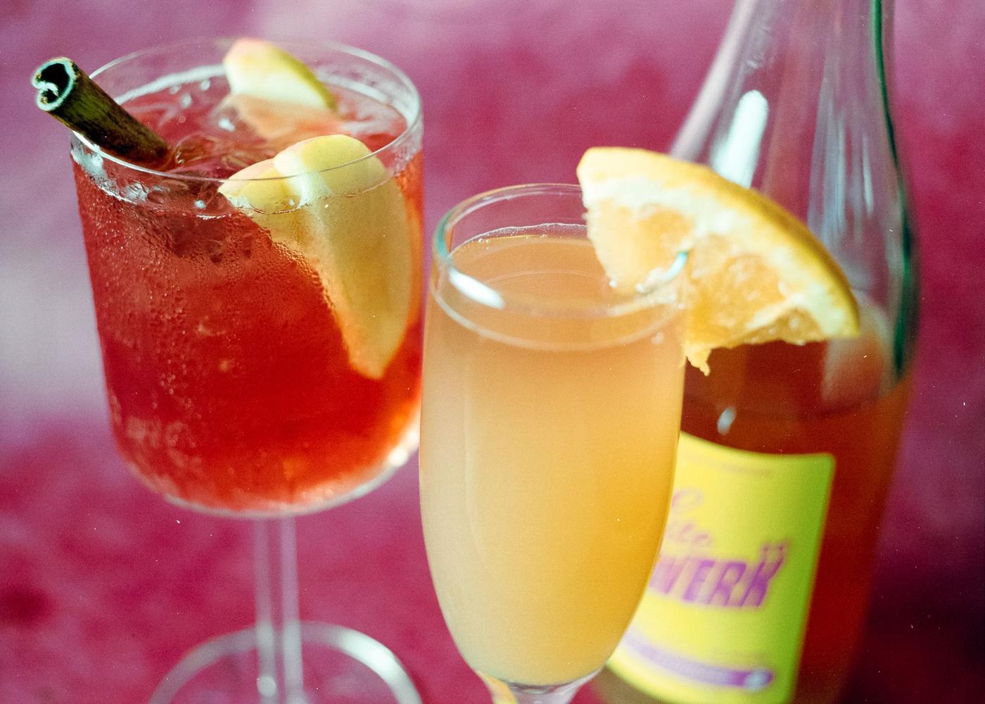 Two cocktails and a bottle on magenta