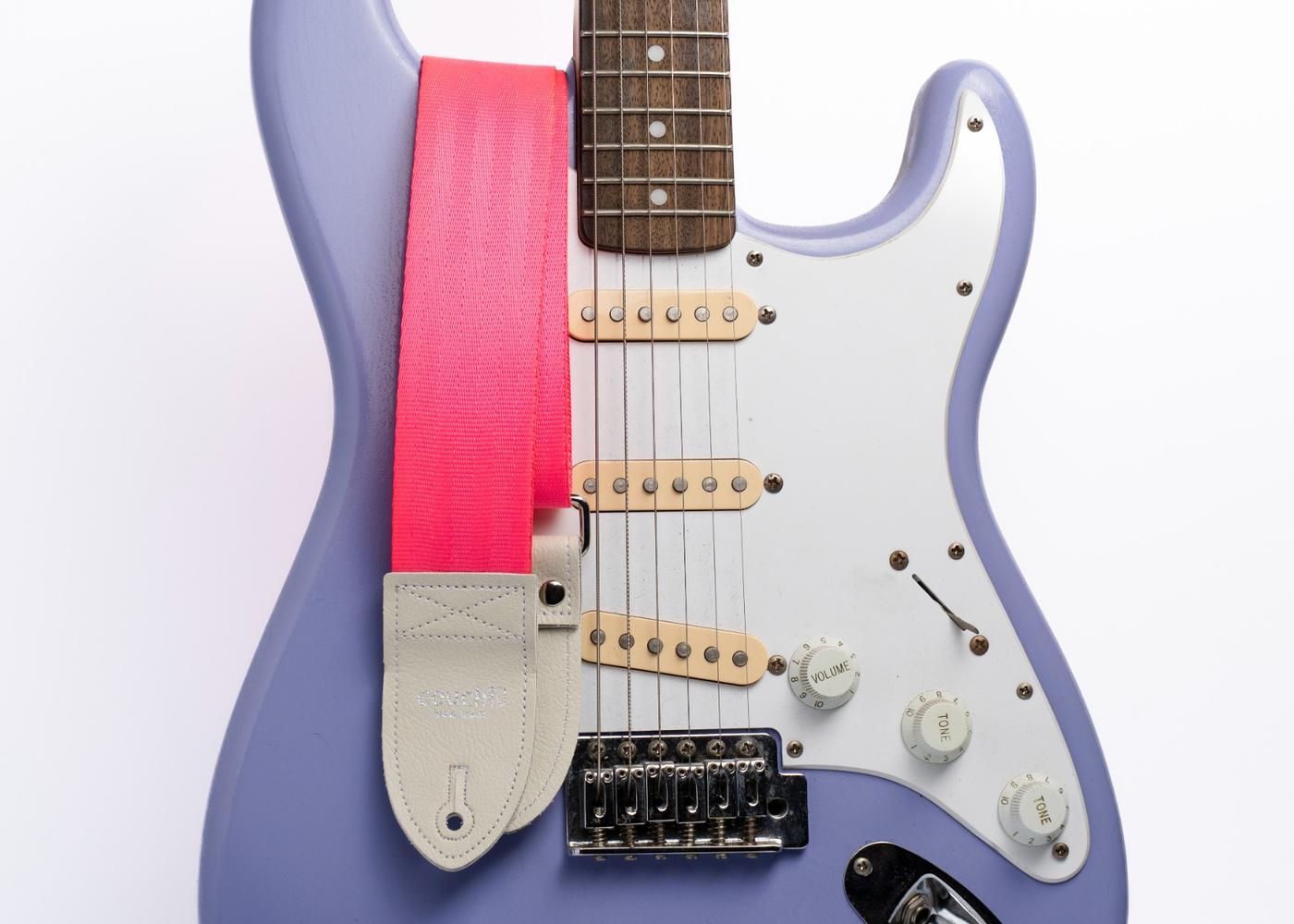 Hot pink strap on a lavender guitar