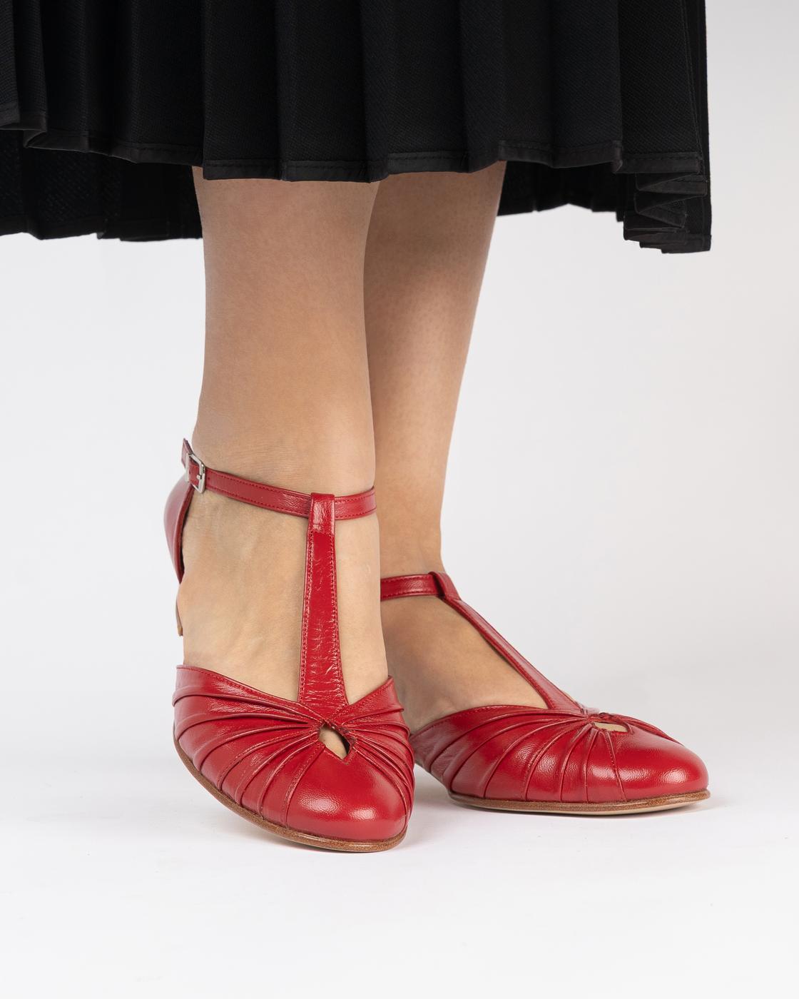 Red Volare shoes worn under a black pleated skirt