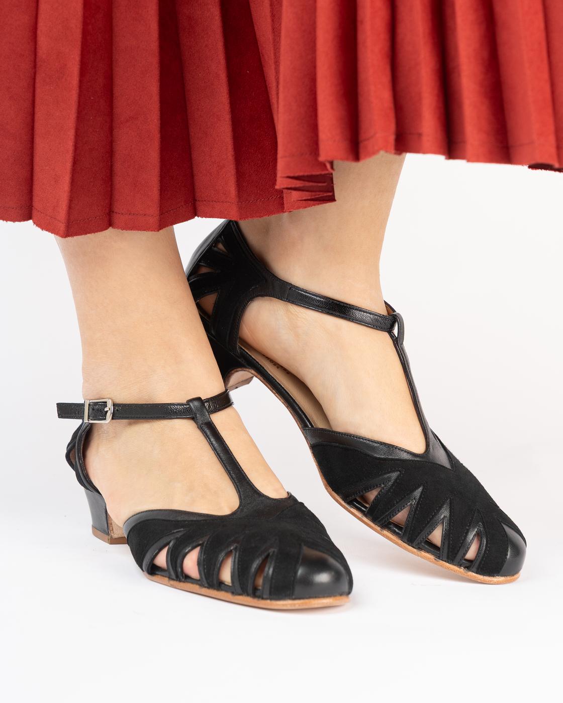 Black cutout Volare shoes worn under a red pleated skirt